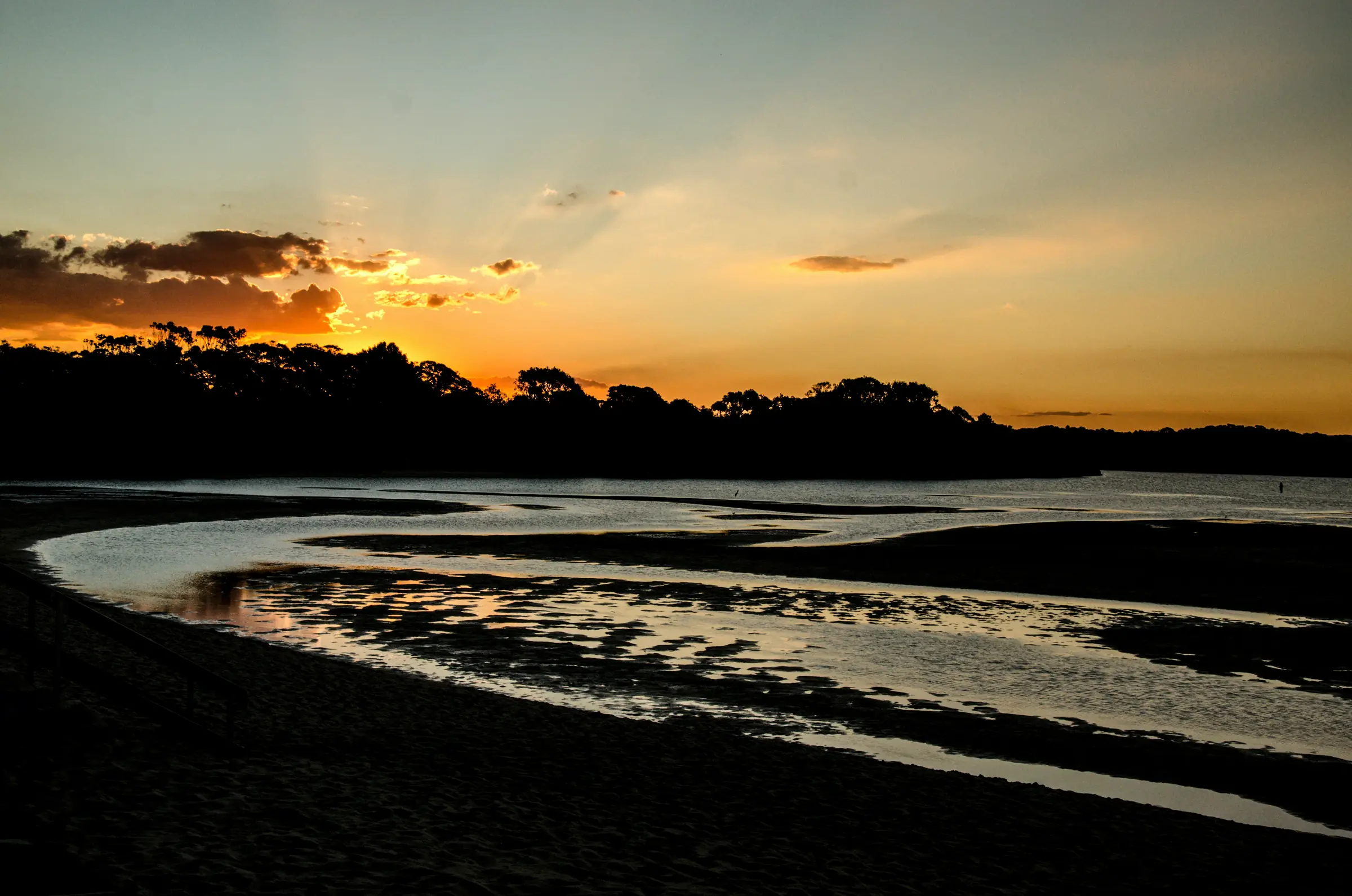 Coastal sunset with sand patterns and reflections