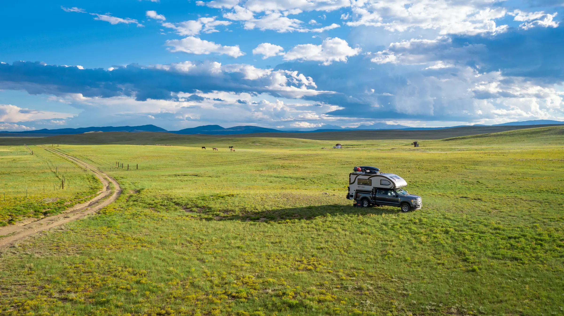 Aerial view of a camper on open grasslands under clouds